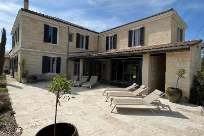 Miniature Location salle Tresses (Gironde) - Domaine de la Rose Blanche #25 Façade d'une maison en pierre avec terrasse ensoleillée, chaises longues et pots de fleurs sur un sol pavé clair.