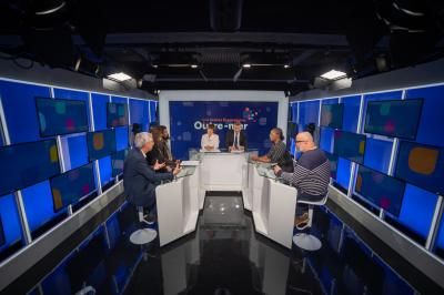 Des personnes échangent dans un espace d'exposition intérieur avec des stands et une structure métallique visible en arrière…