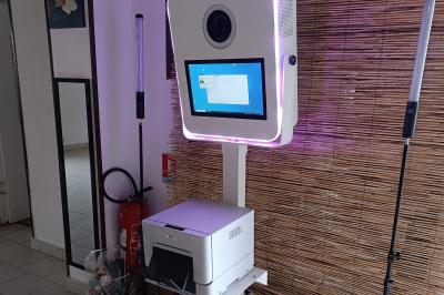 Borne photo en bois sur trépied avec un anneau lumineux allumé, installée dans un espace intérieur.