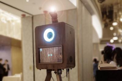 Borne photo en bois sur trépied avec un anneau lumineux allumé, installée dans un espace intérieur.