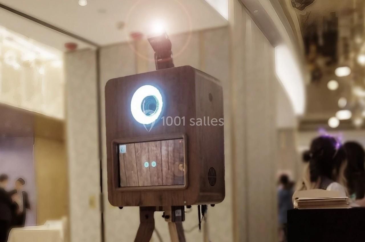 Borne photo en bois sur trépied avec un anneau lumineux allumé, installée dans un espace intérieur.