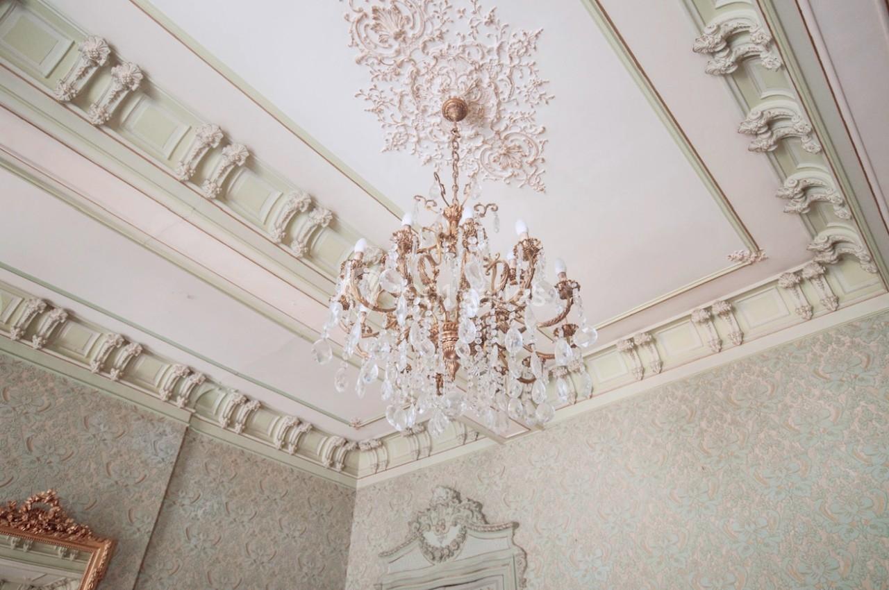 Plafond orné avec moulures décoratives et lustre en cristal suspendu dans une pièce élégante au style classique.