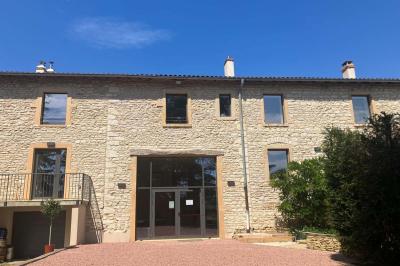 Miniature Location salle Pommiers (Rhône) - Domaine Nicolas Rebut #16 Façade d'un bâtiment en pierre avec de grandes fenêtres, une entrée vitrée et une cour en gravier sous un ciel bleu.