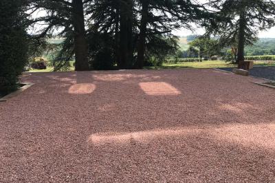 Miniature Location salle Pommiers (Rhône) - Domaine Nicolas Rebut #15 Façade d'un bâtiment en pierre avec de grandes fenêtres, une entrée vitrée et une cour en gravier sous un ciel bleu.