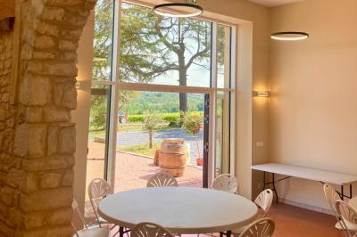 Miniature Location salle Pommiers (Rhône) - Domaine Nicolas Rebut #12 Façade d'un bâtiment en pierre avec de grandes fenêtres, une entrée vitrée et une cour en gravier sous un ciel bleu.