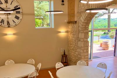 Miniature Location salle Pommiers (Rhône) - Domaine Nicolas Rebut #11 Façade d'un bâtiment en pierre avec de grandes fenêtres, une entrée vitrée et une cour en gravier sous un ciel bleu.