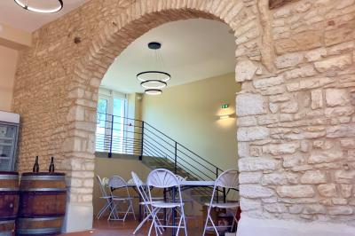 Miniature Location salle Pommiers (Rhône) - Domaine Nicolas Rebut #2 Façade d'un bâtiment en pierre avec de grandes fenêtres, une entrée vitrée et une cour en gravier sous un ciel bleu.