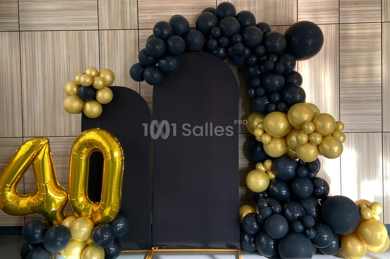 Décoration avec ballons noirs et dorés formant une arche, accompagnée du chiffre 40 en ballons dorés.