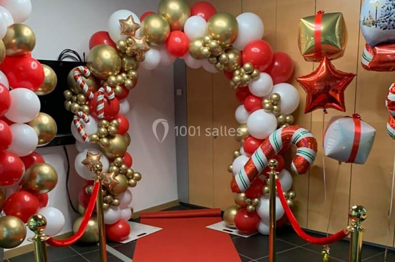Arche décorative en ballons rouges, blancs et dorés avec cannes en sucre, entourée de rubans et de ballons étoilés.
