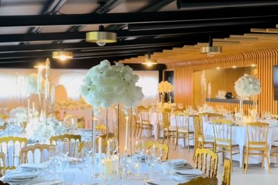 Miniature Deco Events #2 Salle de réception élégante avec tables rondes décorées de nappes blanches, chaises dorées et centres de table fleuris.