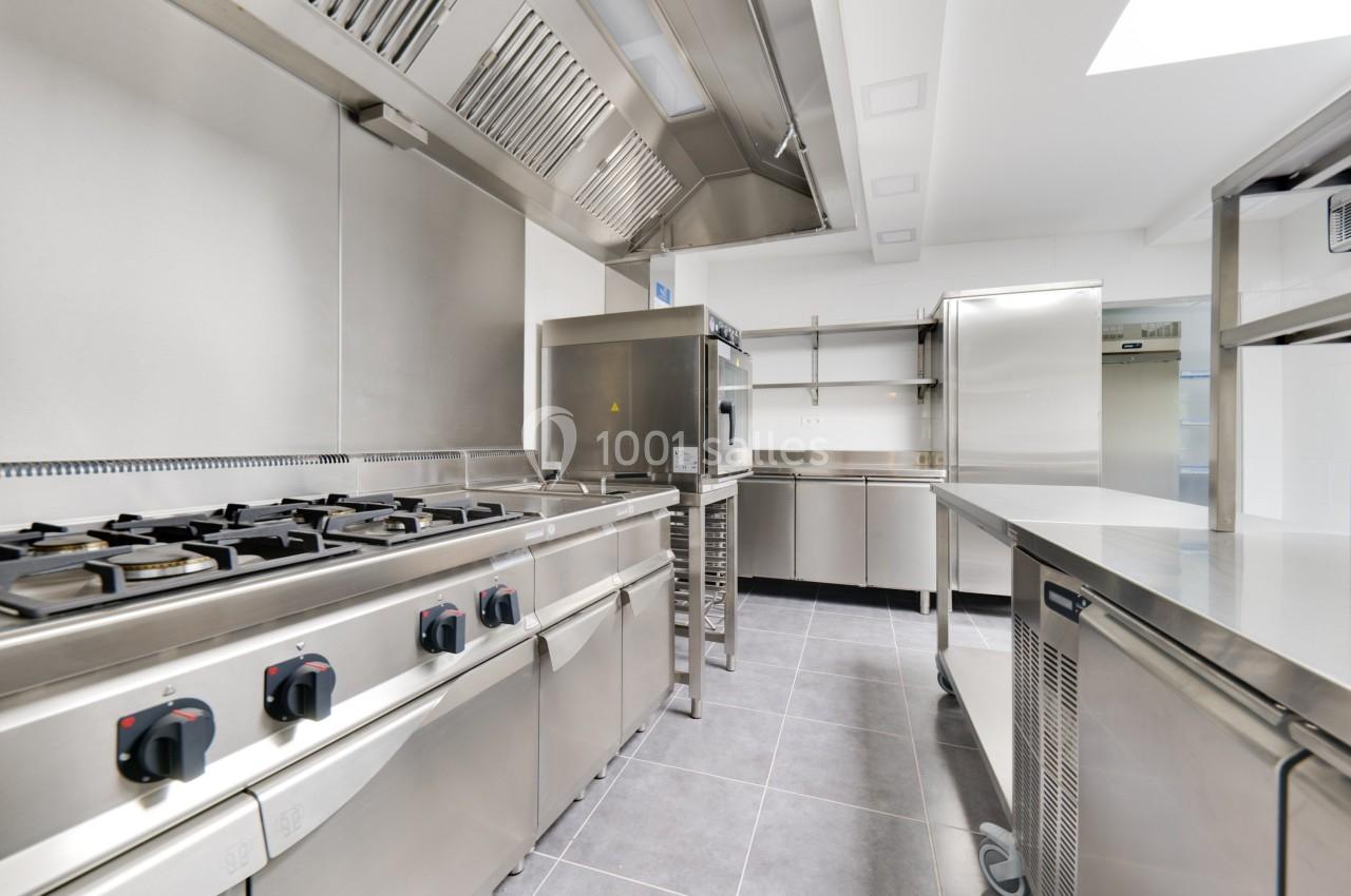 Cuisine professionnelle moderne avec équipements en acier inoxydable, incluant plaques de cuisson, fours et plans de travail.
