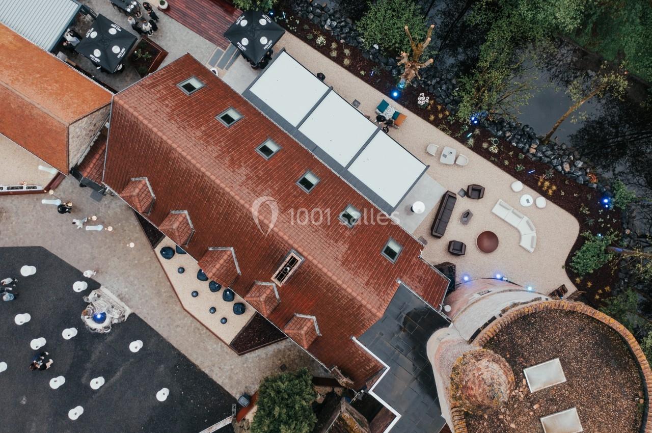 Vue aérienne d'un bâtiment en briques rouges avec une cour aménagée et des espaces extérieurs entourés de verdure.