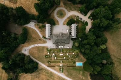 Miniature Location salle Grez-Doiceau (Brabant wallon) - Château de Laurensart #3 Salle élégante avec un lustre imposant, table ronde en bois, chaises vertes et grandes fenêtres encadrées de rideaux.