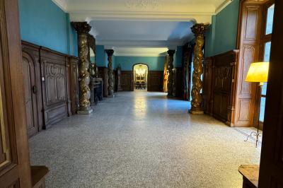 Miniature Location salle Grez-Doiceau (Brabant wallon) - Château de Laurensart #9 Salle élégante avec un lustre imposant, table ronde en bois, chaises vertes et grandes fenêtres encadrées de rideaux.