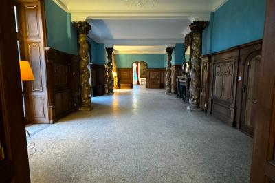 Miniature Location salle Grez-Doiceau (Brabant wallon) - Château de Laurensart #8 Salle élégante avec un lustre imposant, table ronde en bois, chaises vertes et grandes fenêtres encadrées de rideaux.