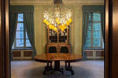 Miniature Location salle Grez-Doiceau (Brabant wallon) - Château de Laurensart #10 Salle élégante avec un lustre imposant, table ronde en bois, chaises vertes et grandes fenêtres encadrées de rideaux.