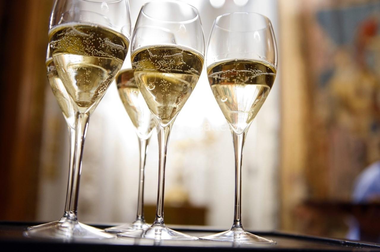Quatre flûtes de champagne remplies, posées sur un plateau, avec un arrière-plan flou et lumineux.