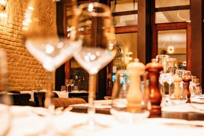 Salle de restaurant avec tables dressées, banquettes en bois, bar en bois et étagères garnies de verres et bouteilles.