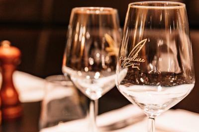 Salle de restaurant avec tables dressées, banquettes en bois, bar en bois et étagères garnies de verres et bouteilles.
