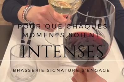 Salle de restaurant avec tables dressées, banquettes en bois, bar en bois et étagères garnies de verres et bouteilles.