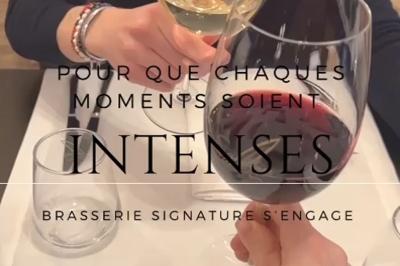 Salle de restaurant avec tables dressées, banquettes en bois, bar en bois et étagères garnies de verres et bouteilles.