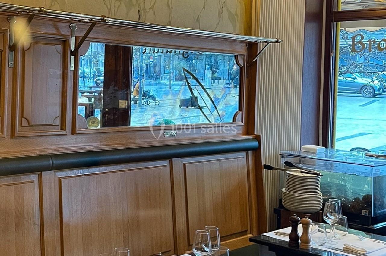Intérieur d'un restaurant avec des tables dressées, un miroir mural et une vue partielle sur l'extérieur.