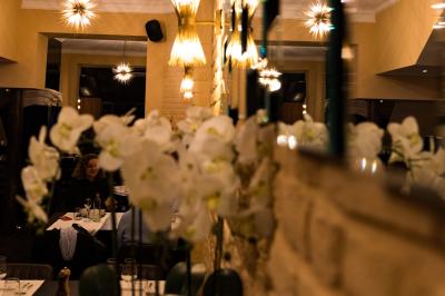 Salle de restaurant avec tables dressées, banquettes en bois, bar en bois et étagères garnies de verres et bouteilles.