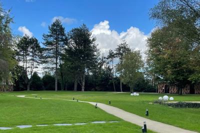 Lit avec des draps blancs, serviettes pliées au premier plan et mur décoré de branches et papillons colorés.