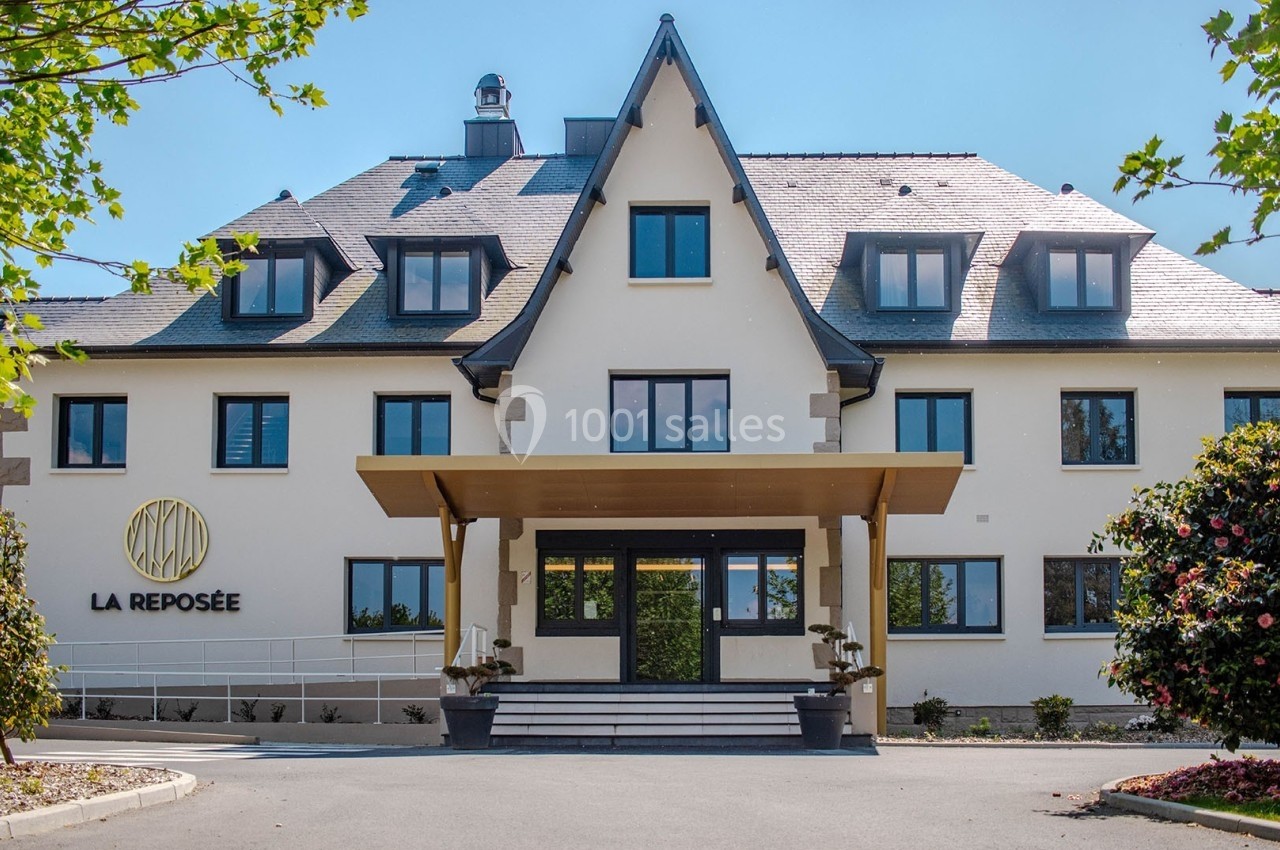 Façade d'un bâtiment moderne avec toit en ardoise, entrée principale couverte et logo ’La Reposée’ sur le mur.