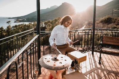 Un homme joue de la guitare acoustique en extérieur, entouré de verdure et de décorations florales.