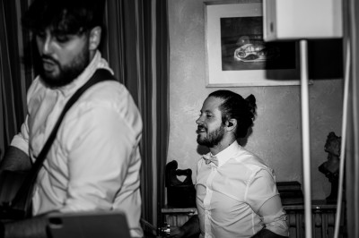 Un homme joue de la guitare acoustique en extérieur, entouré de verdure et de décorations florales.