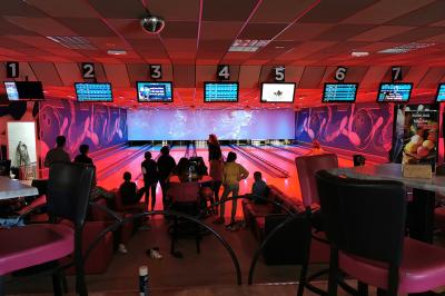 Salle de réception avec une longue table dressée, des chaises rouges et noires, et une fresque murale représentant un…