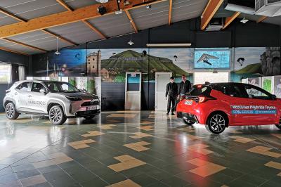 Salle de réception avec une longue table dressée, des chaises rouges et noires, et une fresque murale représentant un…