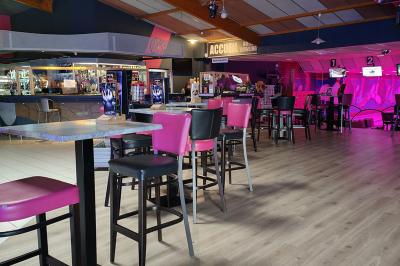 Salle de réception avec une longue table dressée, des chaises rouges et noires, et une fresque murale représentant un…