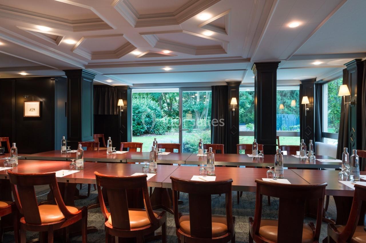 Salle de réunion lumineuse avec une grande table en bois, chaises assorties et vue sur un jardin verdoyant.