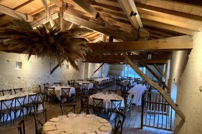 Vue sur un jardin avec pelouse, allées en gravier, parterre de fleurs rouges et bâtiments en pierre sous un ciel dégagé.