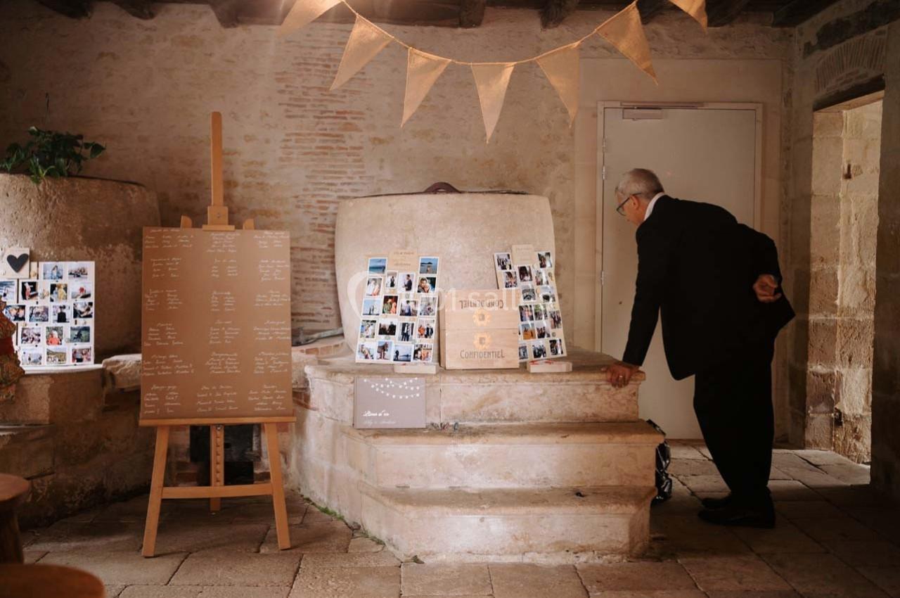 Un homme observe un tableau d'affichage de photos et de noms dans une salle en pierre décorée pour un événement.