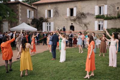 Vue sur un jardin avec pelouse, allées en gravier, parterre de fleurs rouges et bâtiments en pierre sous un ciel dégagé.