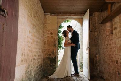 Vue sur un jardin avec pelouse, allées en gravier, parterre de fleurs rouges et bâtiments en pierre sous un ciel dégagé.