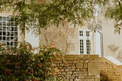 Vue sur un jardin avec pelouse, allées en gravier, parterre de fleurs rouges et bâtiments en pierre sous un ciel dégagé.