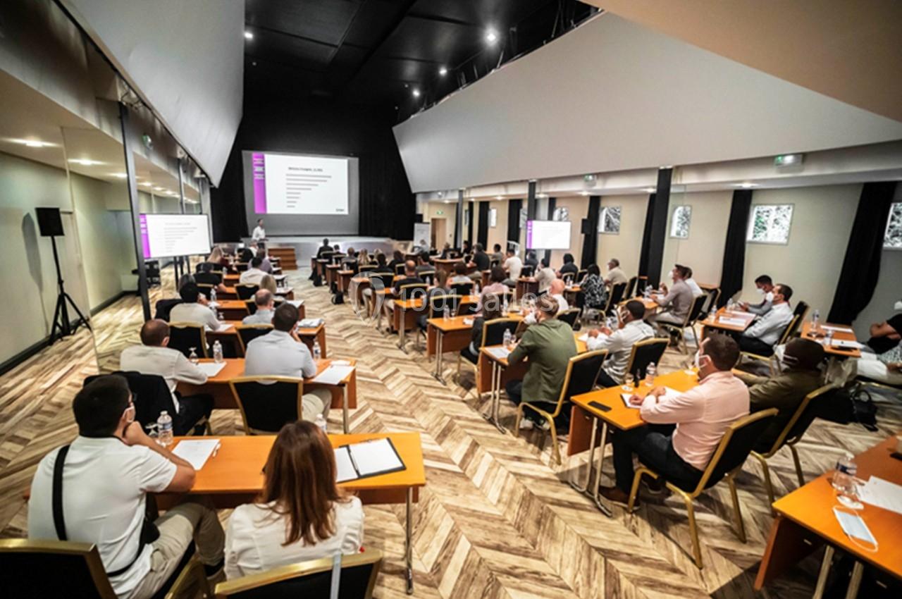 Des personnes assises dans une salle de conférence suivent une présentation projetée sur un écran.