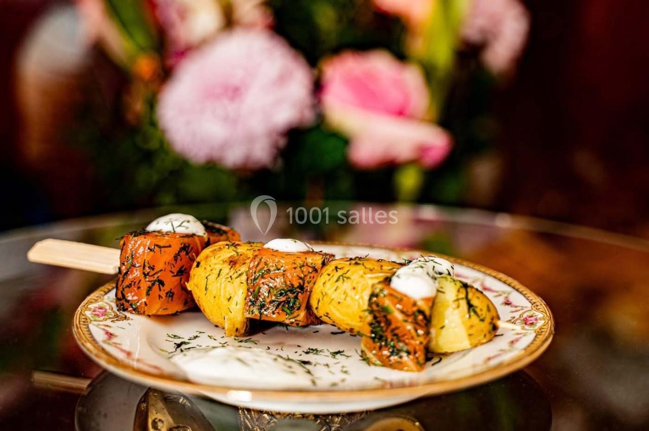 Brochette de pommes de terre et saumon garnie d'aneth et de crème, servie sur une assiette décorative.