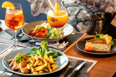 Desserts variés sur une table, incluant un tiramisu décoré d'une tranche d'orange, une mousse au chocolat et un cappuccino.