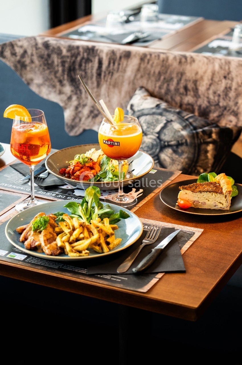 Repas composé de plats variés avec boissons colorées, servi sur une table en bois dans un restaurant.