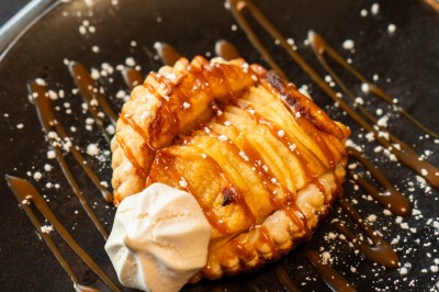 Desserts variés sur une table, incluant un tiramisu décoré d'une tranche d'orange, une mousse au chocolat et un cappuccino.