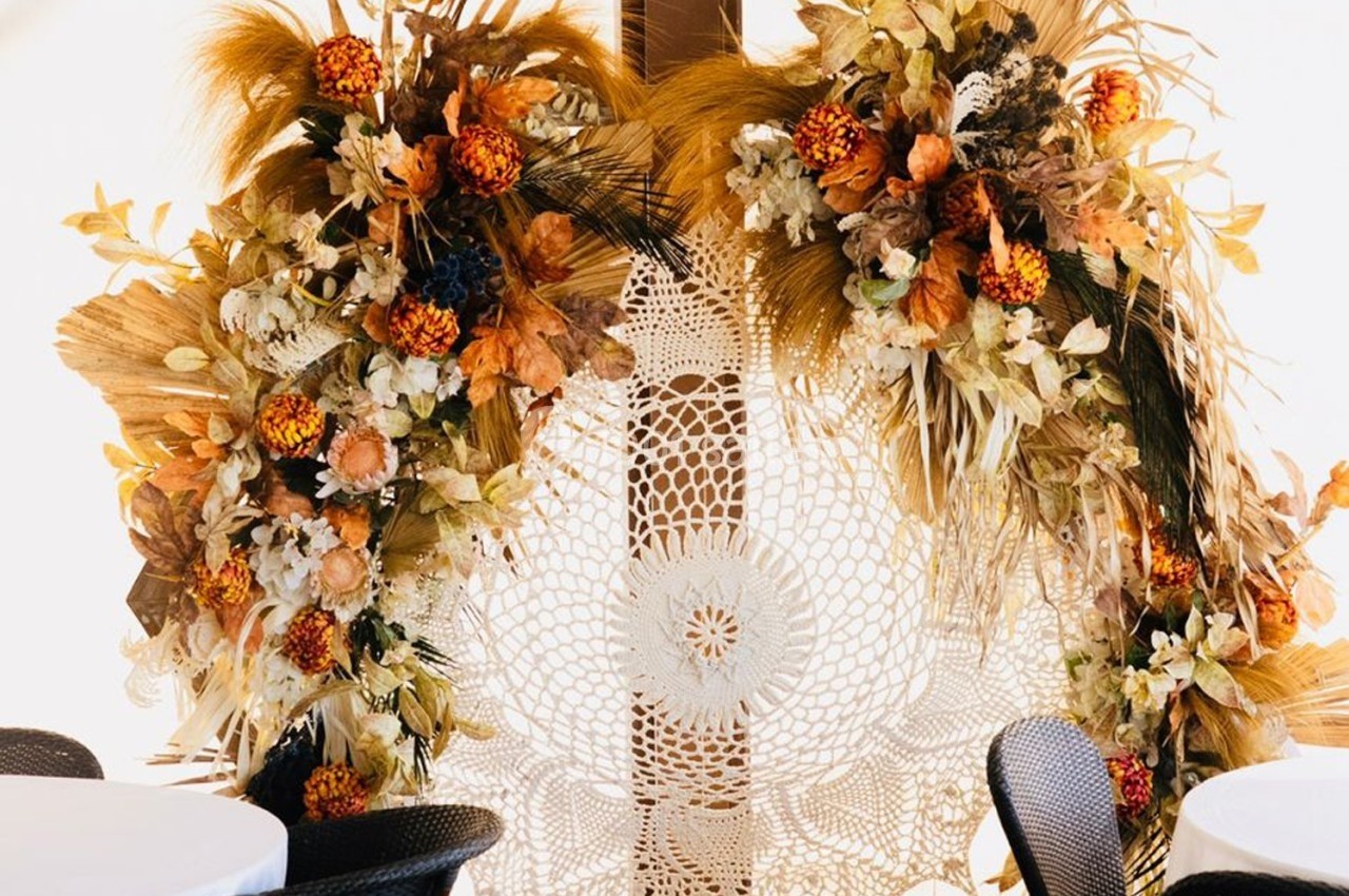 Décoration florale automnale avec des fleurs séchées et un napperon en dentelle en arrière-plan.