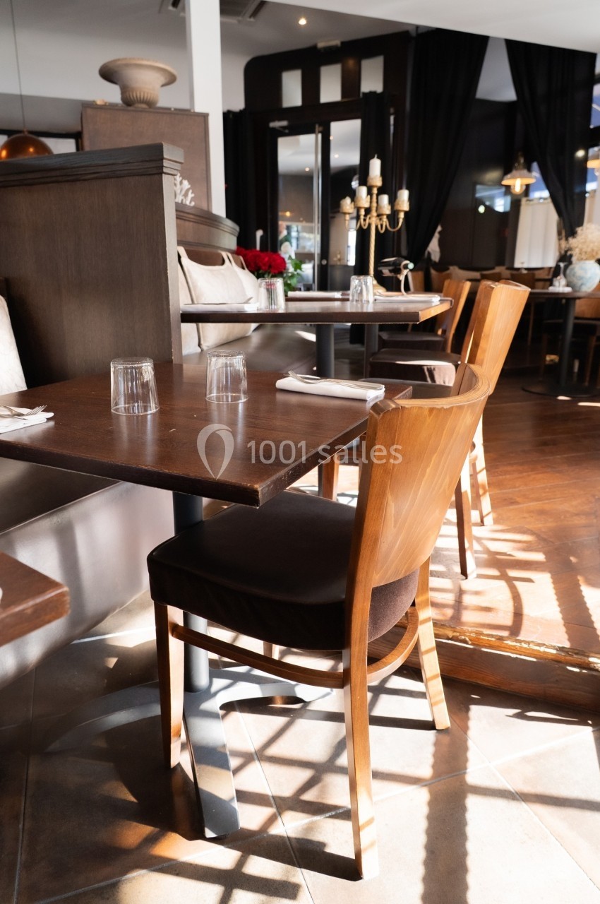 Salle de restaurant lumineuse avec tables en bois, chaises assorties et décoration élégante.