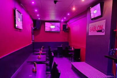 Miniature Location salle Bruxelles (Bruxelles-Capitale) - Karaoke Bar Sablon #6 Écran et panneau indiquant ’Karaoké Bar Sablon’ avec un micro, dans une salle éclairée par des lumières violettes.