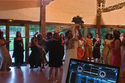 Miniature DJ Montévrain (Seine-et-Marne) - Madisoundlight #15 Des invités dansent autour de la mariée tenant des rubans colorés sous des guirlandes lumineuses dans une salle festive.