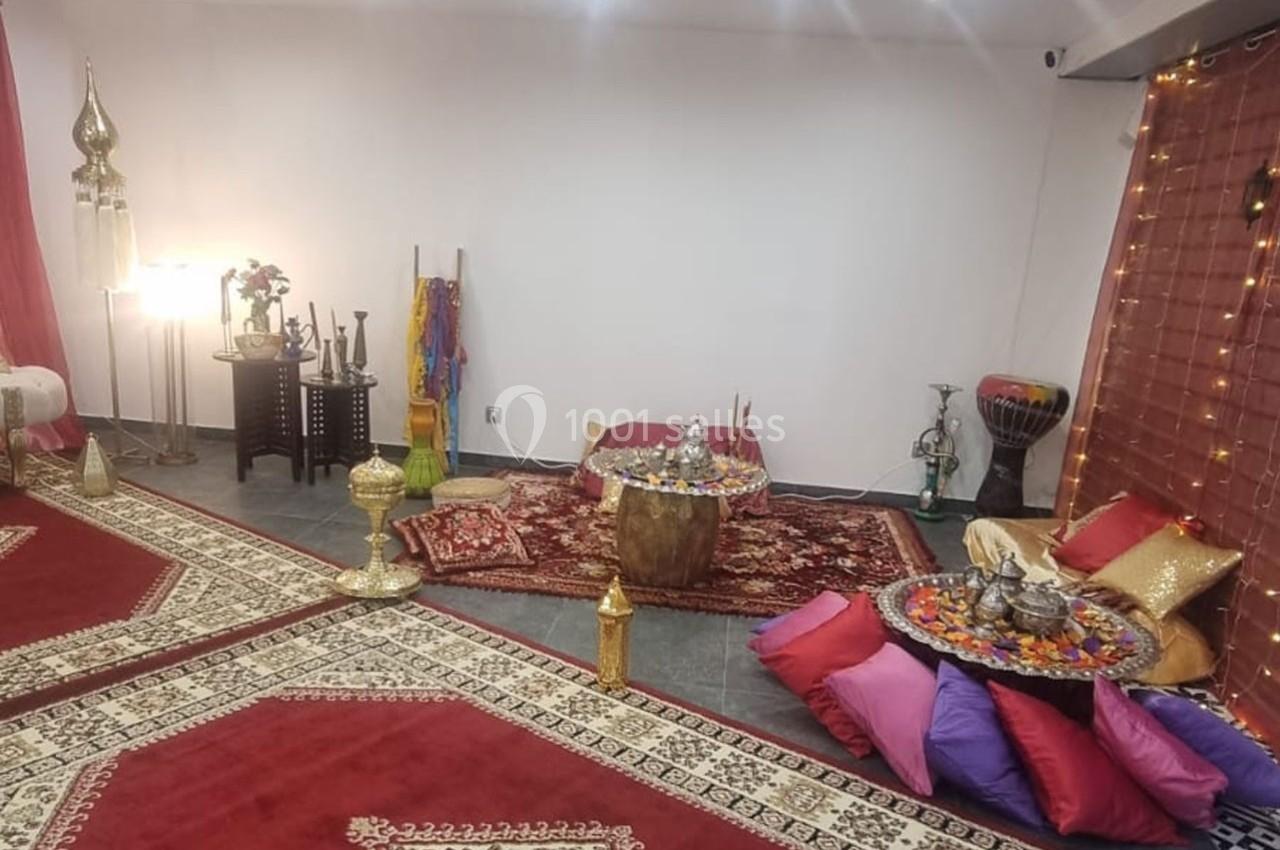 Salle décorée dans un style oriental avec tapis, coussins colorés, lanternes et objets traditionnels.